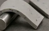 Speckled grey silicone composite strip bent over a metal cylinder